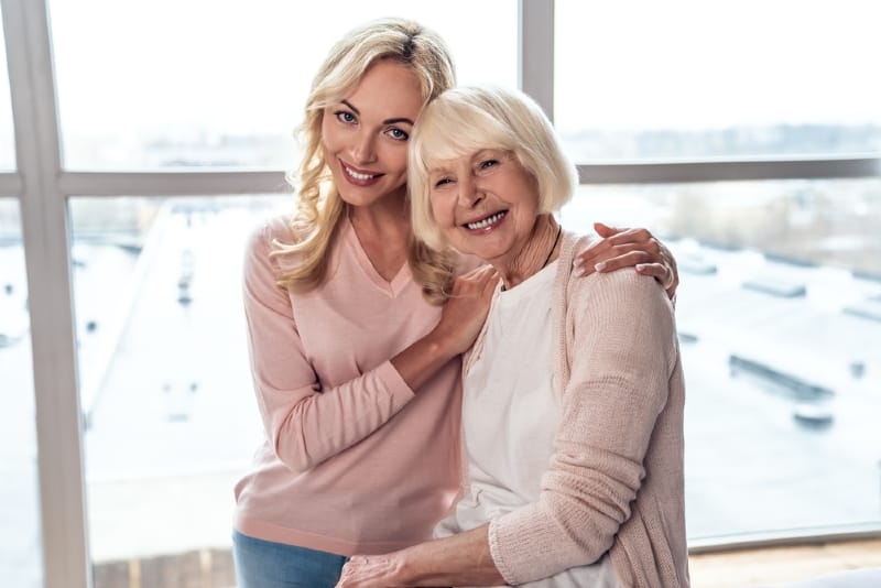 blonde daughter in pink top hugging her mother