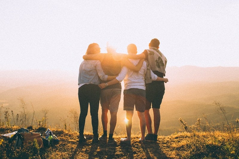 four friends hugging on top of the mountain 
