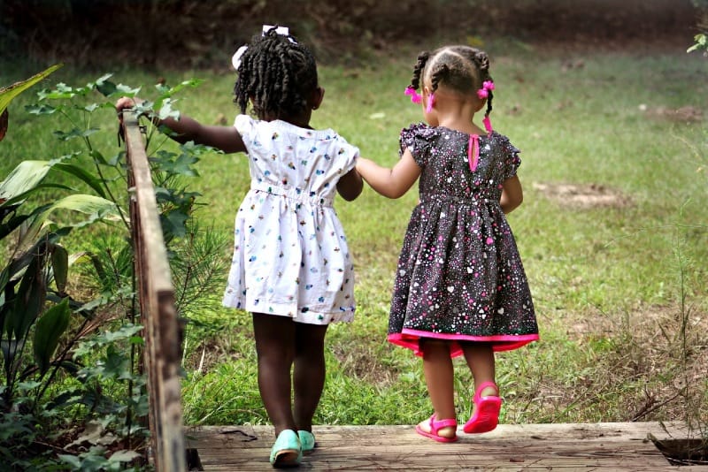 two girls holding hands while crossing bridge