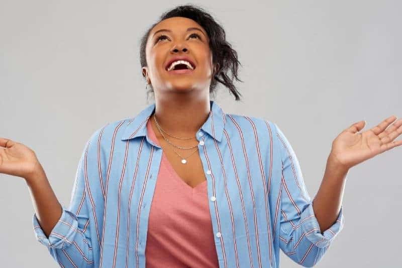 mujer agradecida que levanta las manos sonriendo y levanta la cabeza