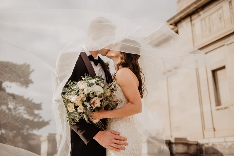 bride holding bouquet of flowers while kissing groom