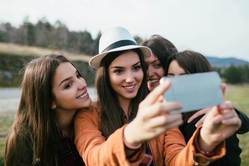 group of female friends taking a groufie during travel near a body of water