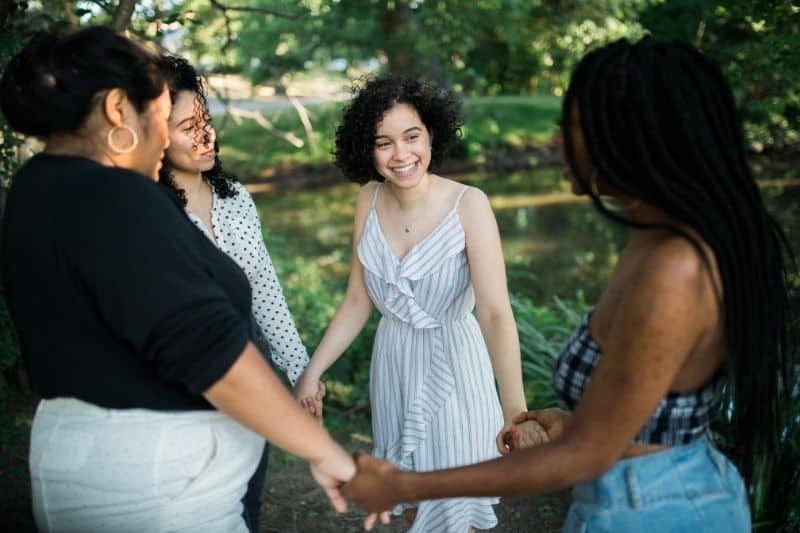 group of women holding hands in circle outdoors