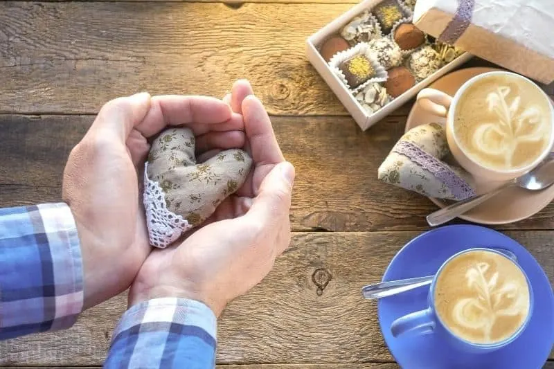 handmade heart in man's hand with chocolates and coffee during a valentine's date