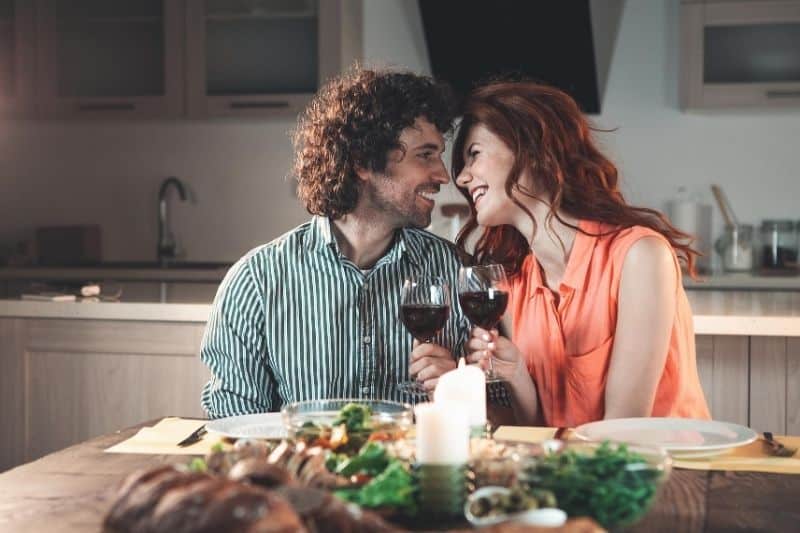 pareja feliz cenando con vela y bebiendo vino