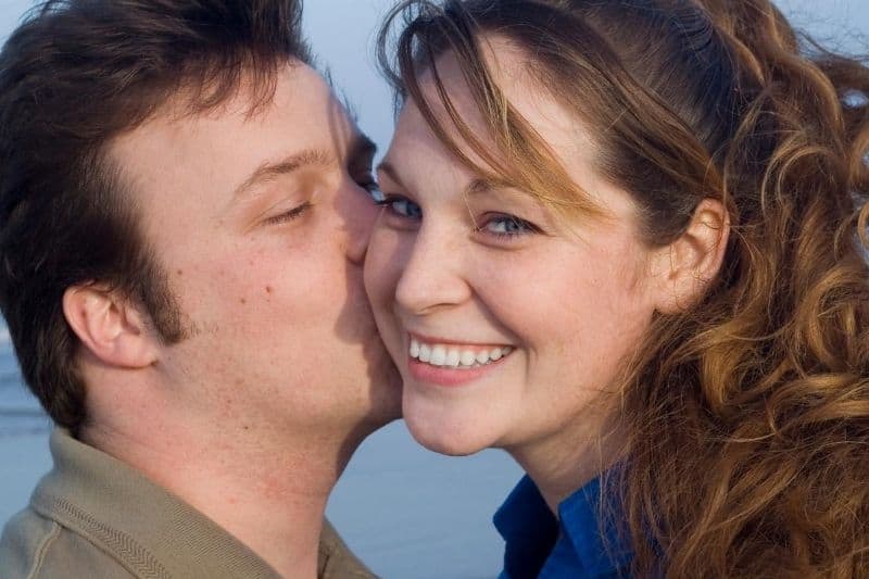 giovane coppia felice che si gode la spiaggia uomo che bacia la donna