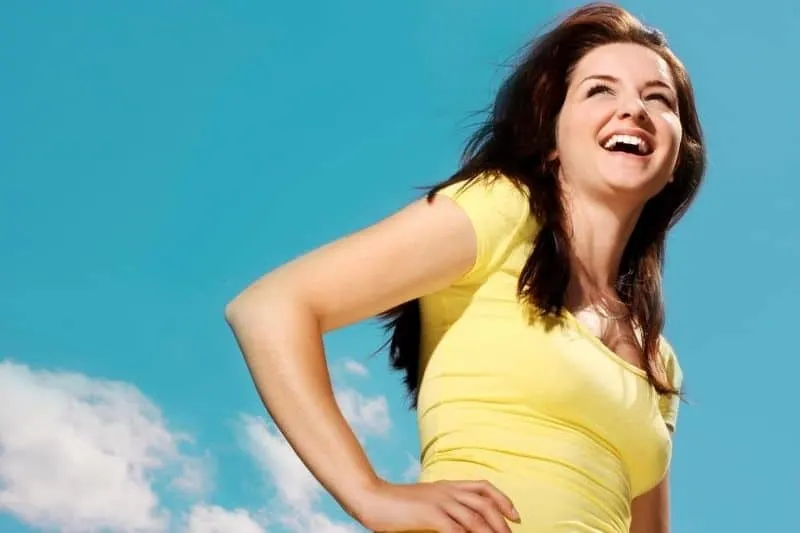 image in low angle on a woman smiling with hands on her waist
