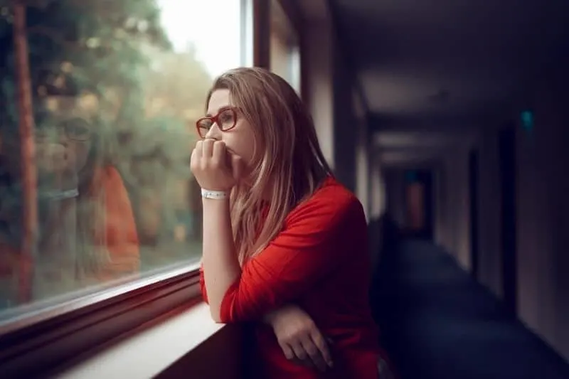 image of a relaxed woman looking outside the window in the hallway