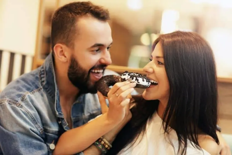 image showing sweet couple eating donut together