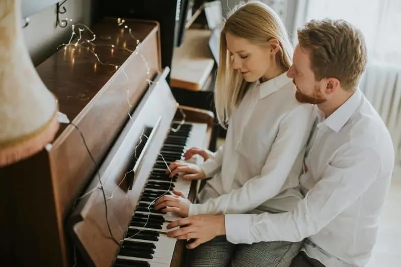 loving couple playing piano where woman sits on man's lap