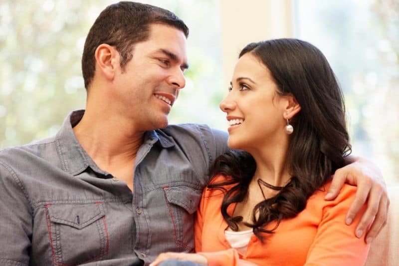 loving hispanic couple sitting in the couch looking eye to eye