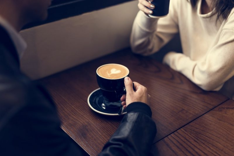 man and woman sitting by the table drinking coffee