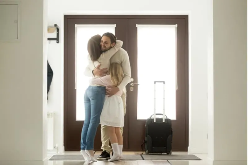 man coming home embraced and greeted by family near the door