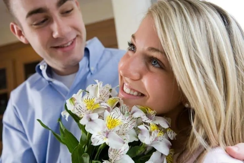 man giving flowers to a woman inside home