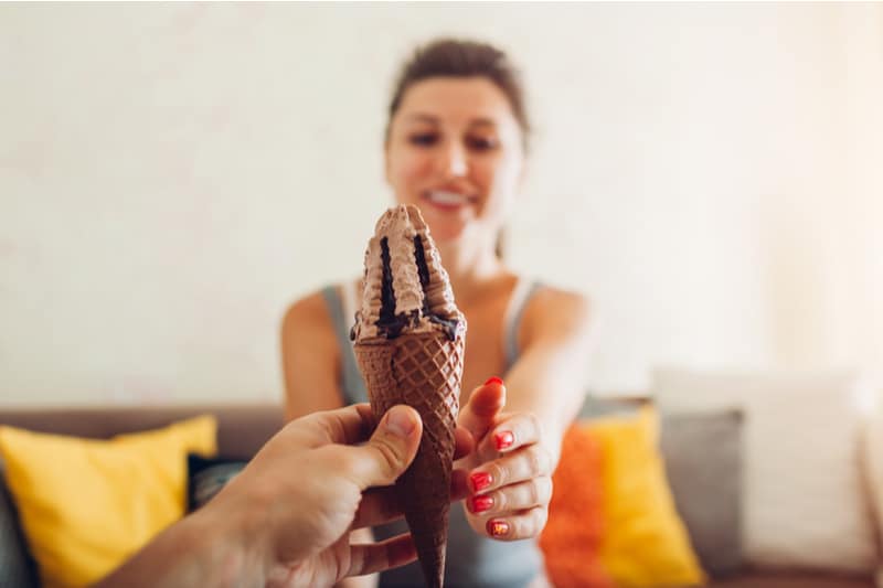 man giving ice cream to a woman sitting on a couch