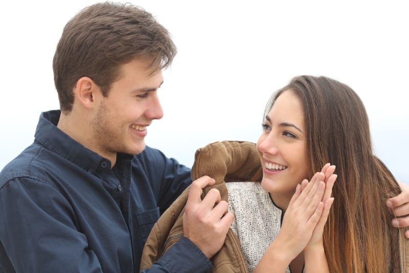 smiling man giving brown jacket to woman
