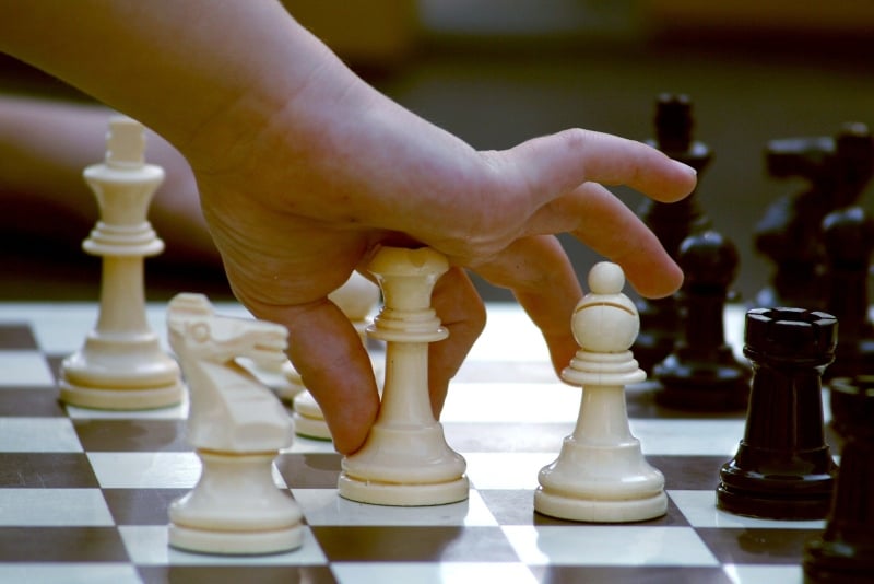 man holding white chess figure
