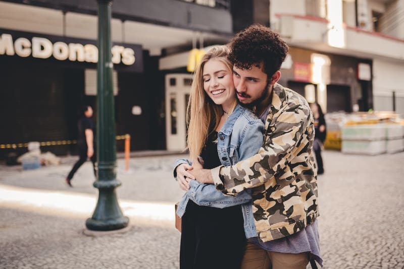man hugging woman while standing on the street