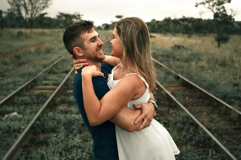 man lifting woman in the middle of the railway track