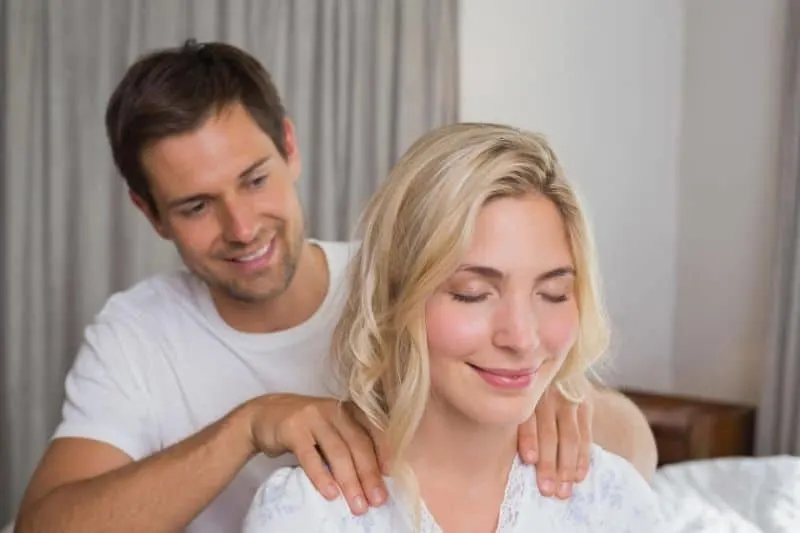 man massaging woman at her back shoulders inside a room