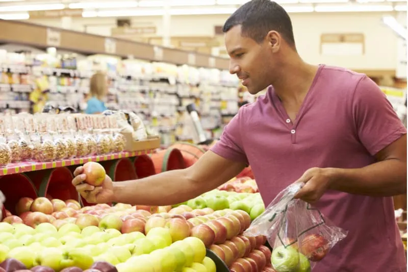 man picking groceries choosing fruits in the fruit section