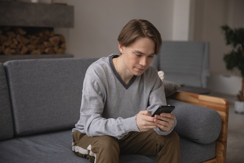 man looking at phone while sitting on couch