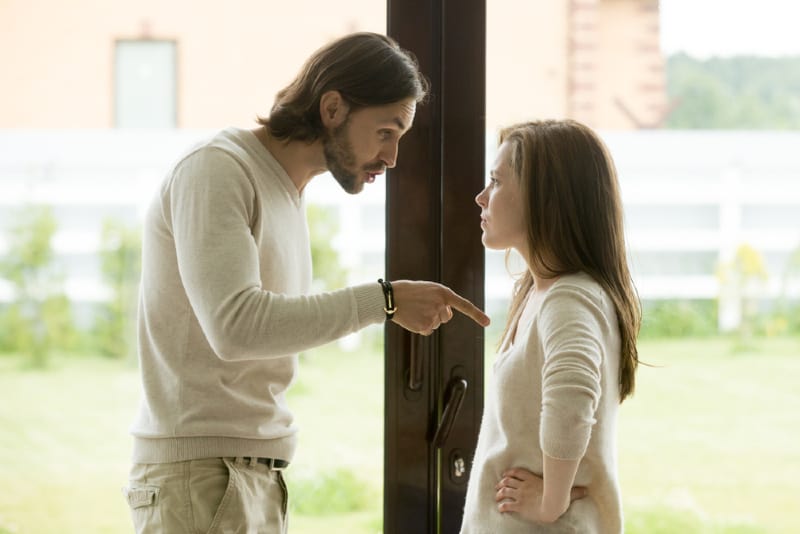 man talking to woman while standing near door