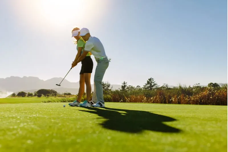man teaching woman to play golf in the golf course
