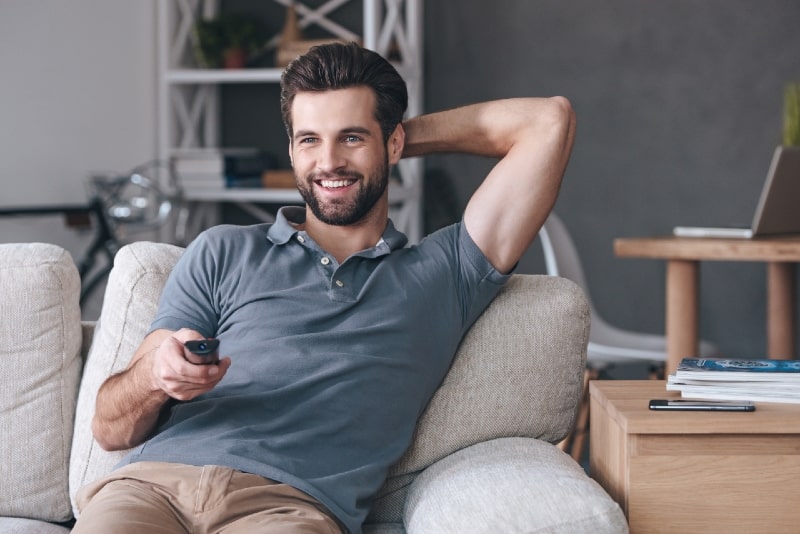 uomo felice che guarda la tv seduto sul divano