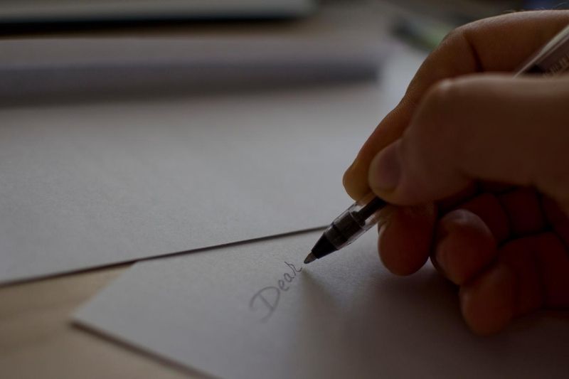 hombre escribiendo una carta a través del papel blanco 