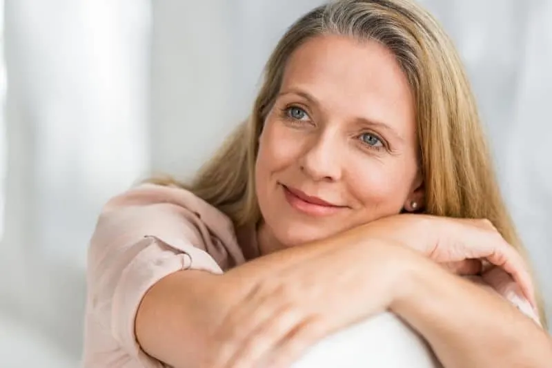 mature woman thinking and smiling while resting on couch