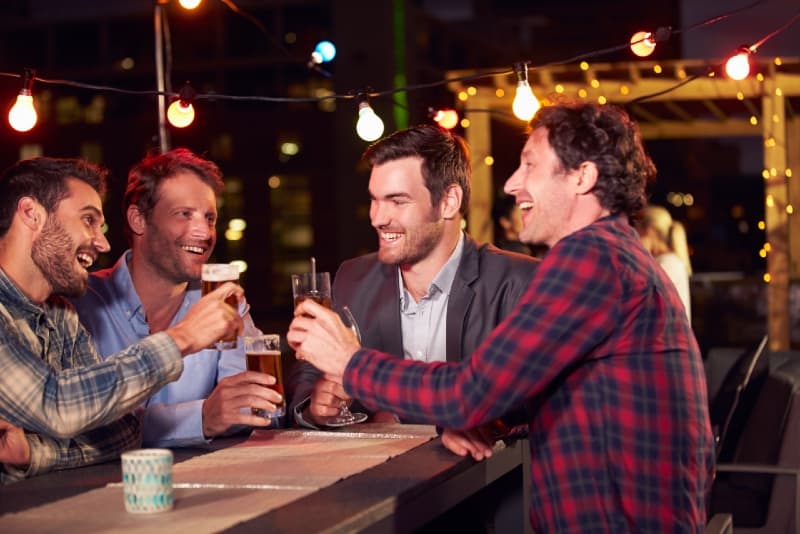 four men drinking beer on rooftop