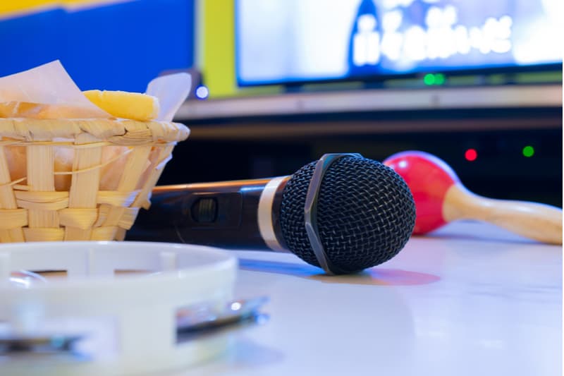 micrófono y pandereta colocados en la mesa cerca de la tv para una sesión de karaoke