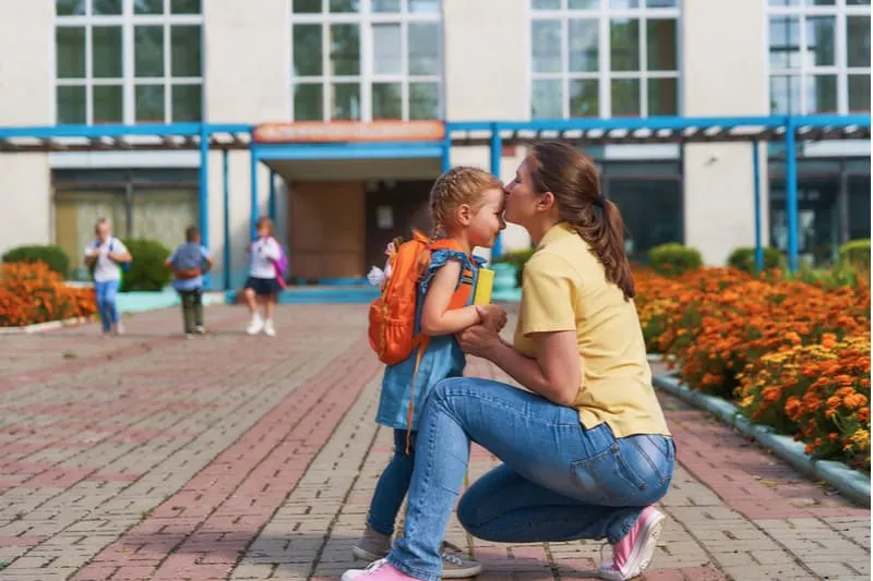mom kisses child before parting for kid to school