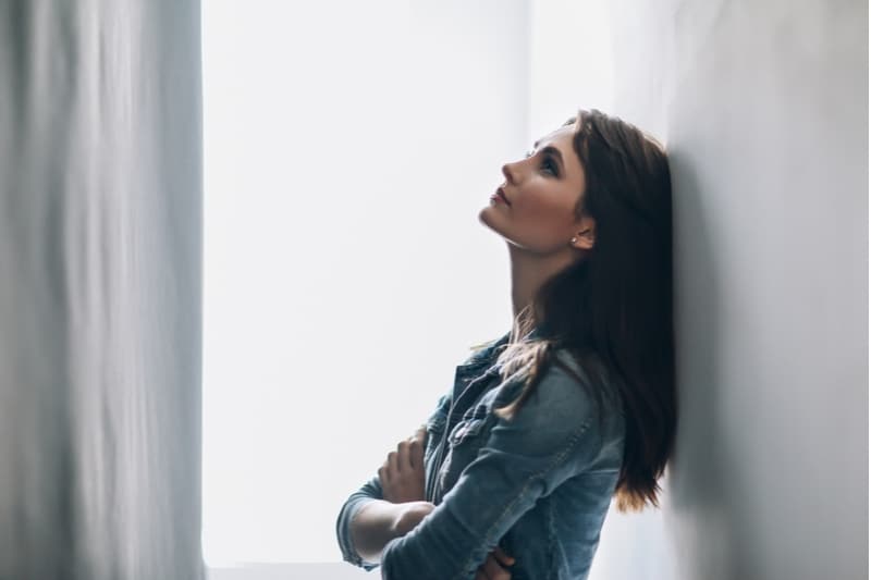 pensive woman leaning on the wall thinking deeply