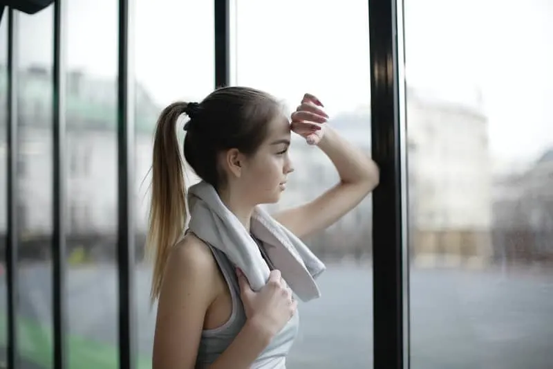 pensive young female in athletic wear looking out thru the gym's glass wall