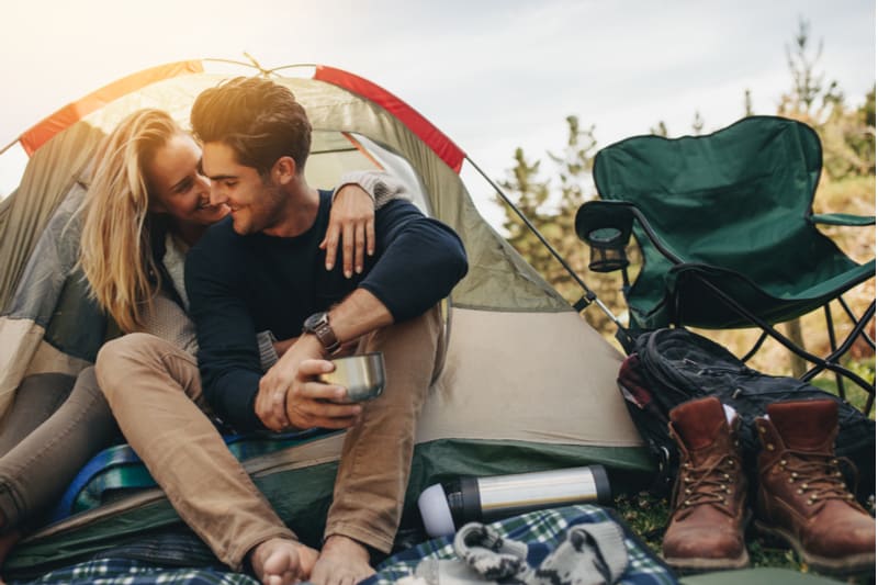 romántica pareja de acampada acurrucada en la tienda con su material de acampada