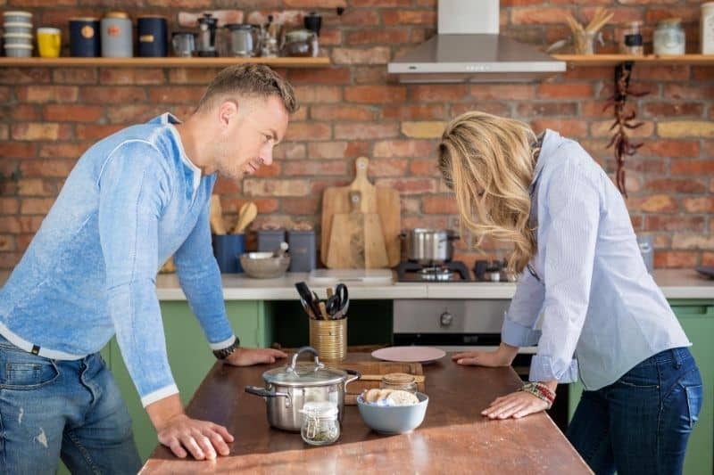 sad couple having an argument inside the kitchen standing