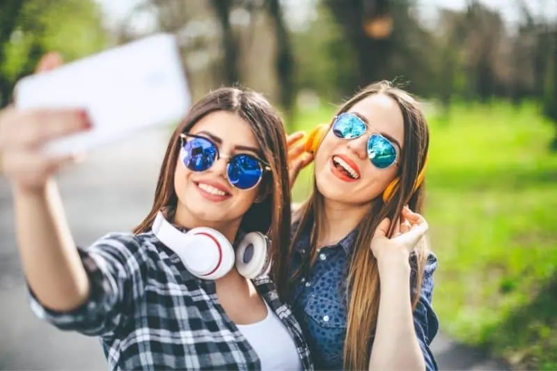 selfie with a friend havinf earphones and sunglasses in the park