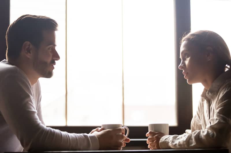 serious couple conversing over a cup of coffee inside a cafe