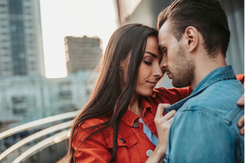 sideview of a calm couple hugging each other outdoors