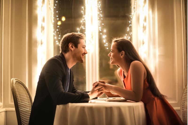 sweet couple having romantic dinner holding hands and eye to eye