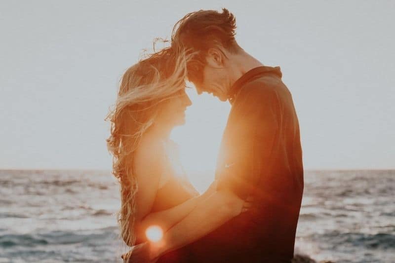 sweet couple hugging by the beach during sunset