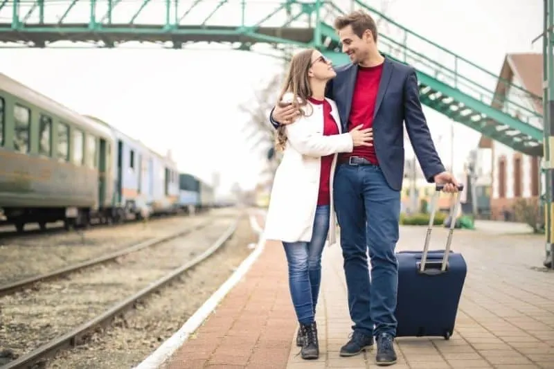 sweet couple walking with baggage along the train railways