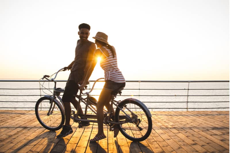 dulce pareja romántica montando en una bicicleta tándem durante la puesta de sol