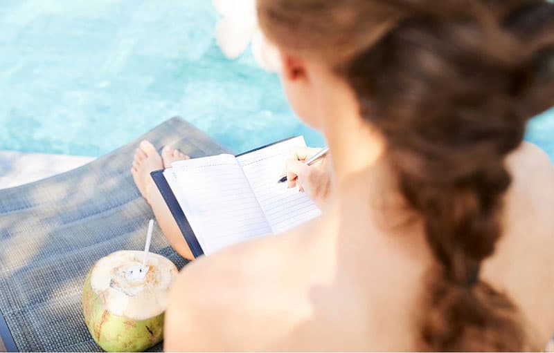 top view of a woman journaling near a swimming pool