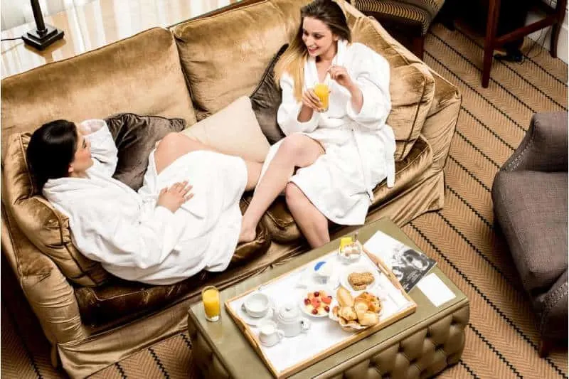 two friends in the spa eating foods while on their bath robe