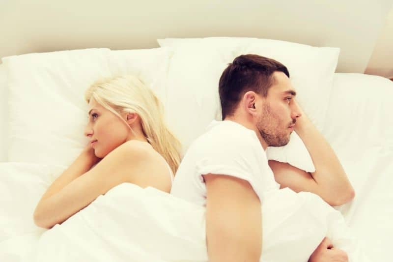 unhappy couple lying in bed facing opposite directions