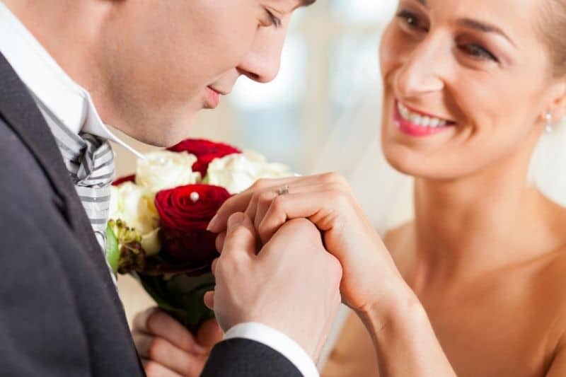coppia di sposi promettente uomo che tiene la mano della donna che porta un buoquet di fiori
