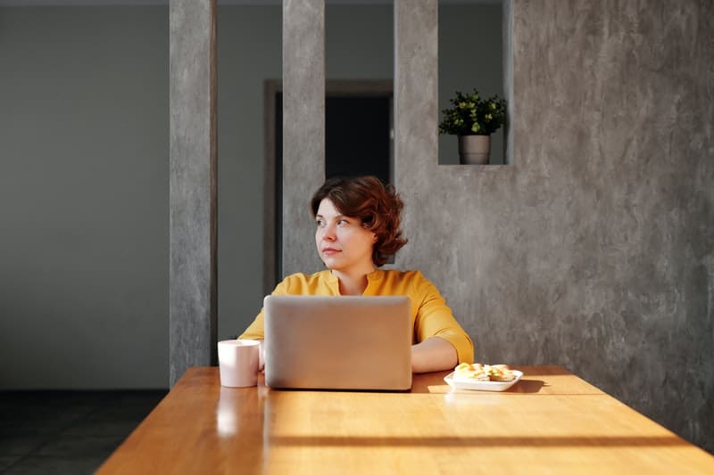 woman at laptop thinking with food on the table 